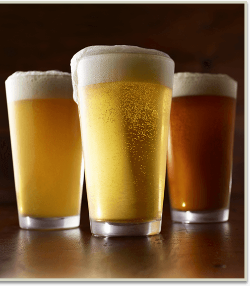 Three beers, two light and one dark with a large head of foam