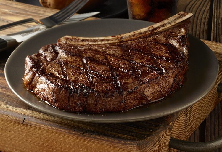 Bone-in steak on a plate with a soda in the background