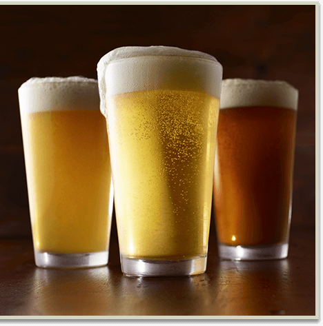 Three beers, two light and one dark with a large head of foam