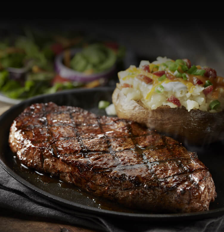 A steak and baked potato on a plate.